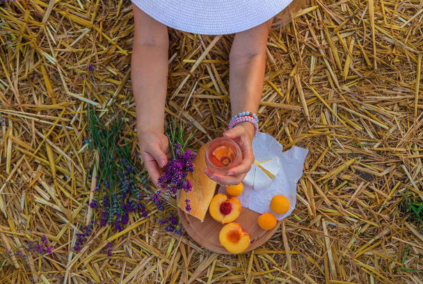 Een vrouw houdt wijn in een bril. Picknick in het lavendelveld. Selectieve focus. aard. - Foto, afbeelding