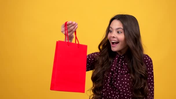 surprised kid long hair is curious about gift in shopping bag, surprise - Footage, Video