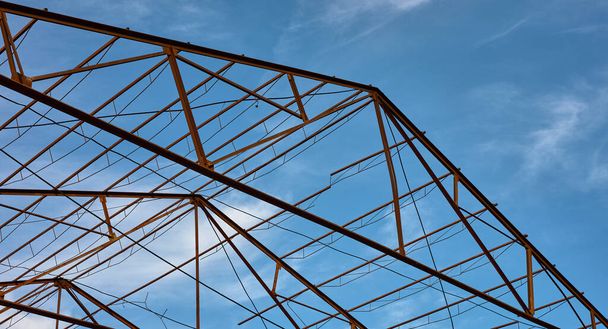 detail of a metal structure of an abandoned roof against a blue sky - 写真・画像