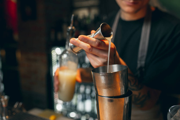 Zbliż obraz. Jeden barman przygotowuje napój alkoholowy w shakerze koktajlowym cieszącym się pracą. - Zdjęcie, obraz