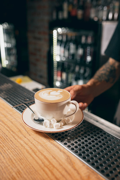 Bílý šálek kávy, latté nebo cappuchino s marshmallow na dřevěné barové lince v kavárně. Zavřít - Fotografie, Obrázek