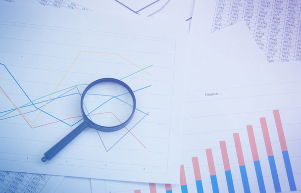 Magnifying glass on charts, graphs and financial statements. Inventory chart analysis and financial accounting. Copy space. Can be used for presentations - Photo, Image