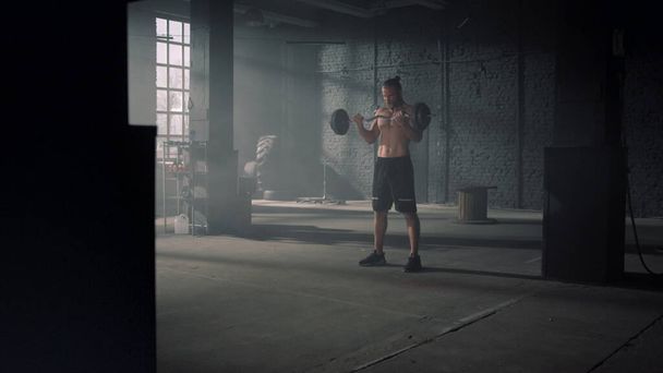 Hombre atlético levantando pesas. Powerlifter haciendo ejercicio de rizo de bíceps de agarre ancho - Foto, Imagen