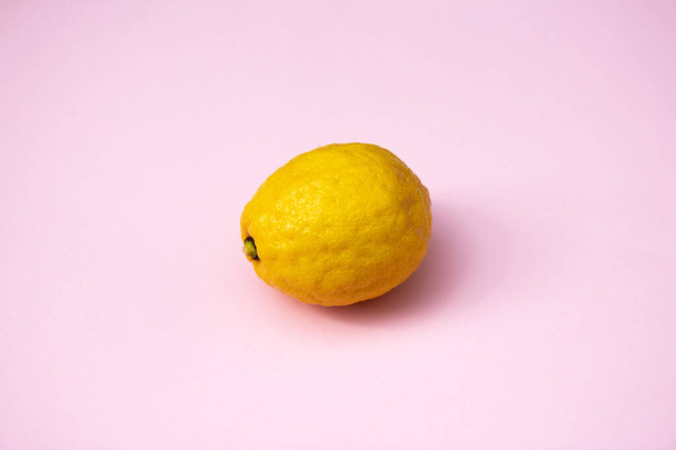 Reife Zitrone. Gelbe Zitrone auf leuchtend rosa Hintergrund. Tropische Früchte im Hintergrund. Frische Zitrusfrüchte - Foto, Bild