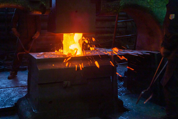 close-up picture of hot steel manual forging process with big mechanical hammer machine - Photo, Image
