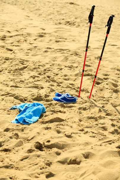 nordic walking. sticks and violet shoes on a sandy beach - Valokuva, kuva
