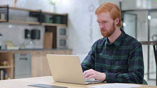 Young Redhead Man in Cafe using Laptop  - Fotó, kép