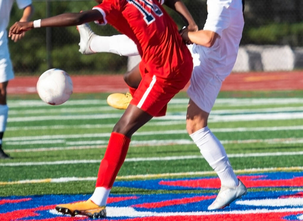 Two high school boys soccer players in a battle for the ball during a game on a turf field. - Photo, Image