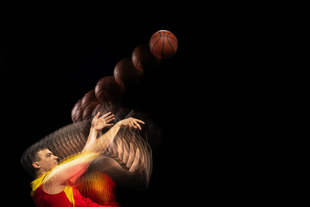 Professional basketball player training with ball isolated on dark background with stroboscope effect. Concept of professional sport, hobby. - Fotó, kép