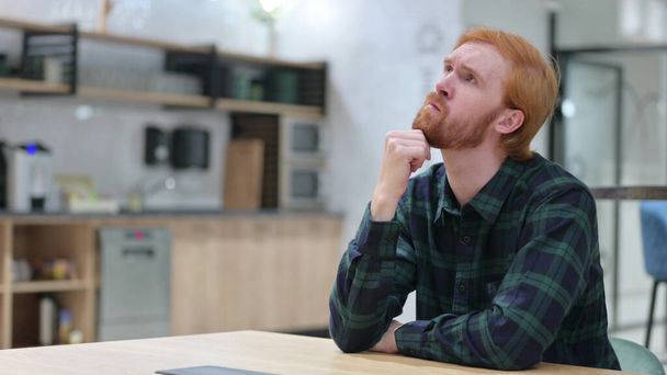 Pensive Redhead Man Sitting and Thinking  - 写真・画像