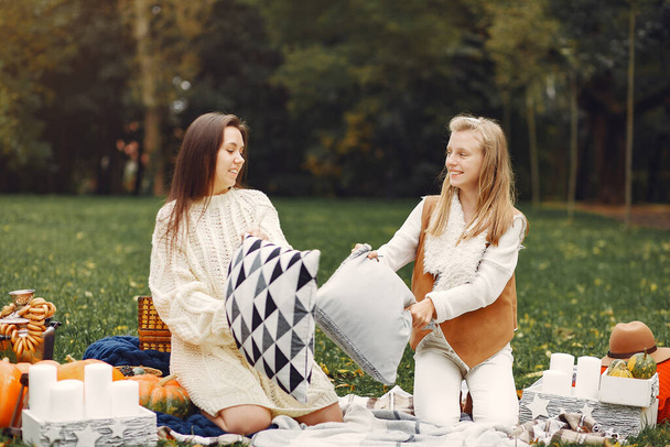 Elegant and stylish girls sitting in a autumn park - Fotó, kép