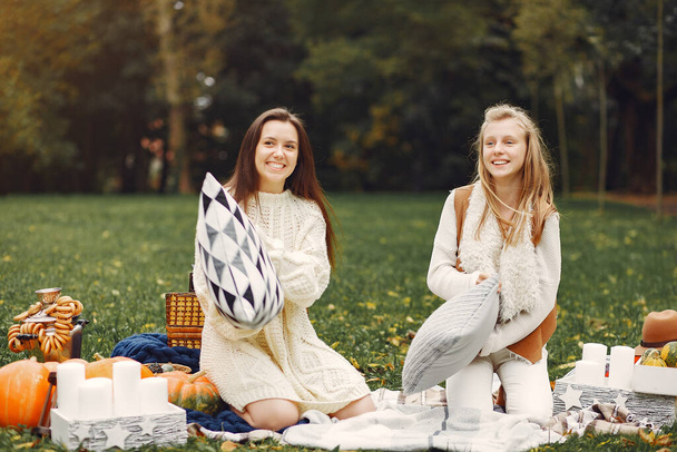 Elegant and stylish girls sitting in a autumn park - Fotó, kép
