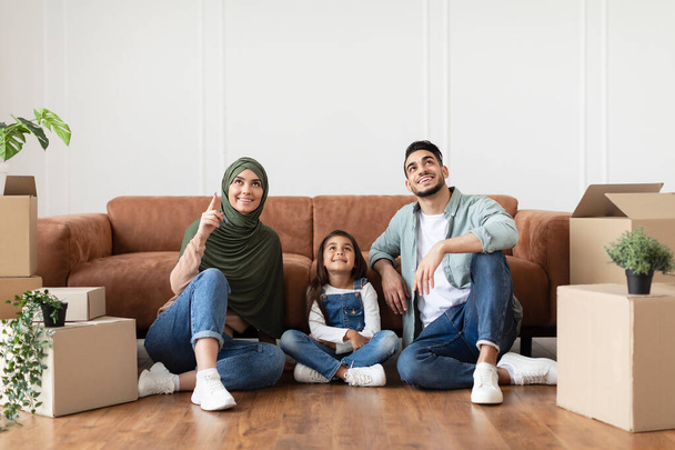 Família muçulmana feliz fazendo reparo em novo apartamento, apontando para cima - Foto, Imagem