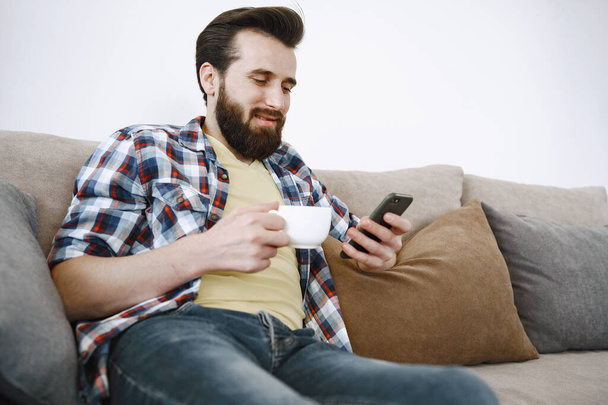 Man drinking coffee and watching TV on couch - Foto, Imagem