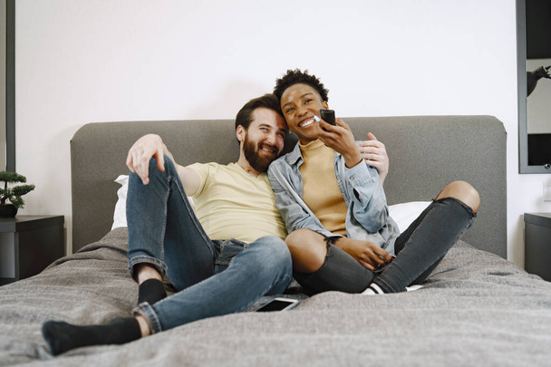 Multiracial pair watching tv together in bed - Photo, Image