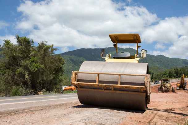 Roller valí čerstvý horký asfalt na nové silnici. Výstavba silnice. Silniční válce pracující na novém staveništi - Fotografie, Obrázek