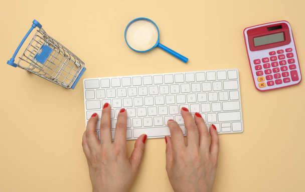 weibliche Hände und weiße drahtlose Tastatur, Stapel von Quittungen und Lupe auf gelbem Hintergrund, Haushaltsanalysekonzept, Einsparungen - Foto, Bild