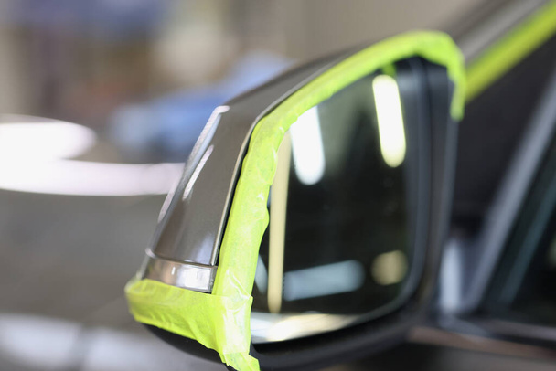 Боковое зеркало автомобиля имеет зеленую защитную ленту для полировки автомобиля - Фото, изображение