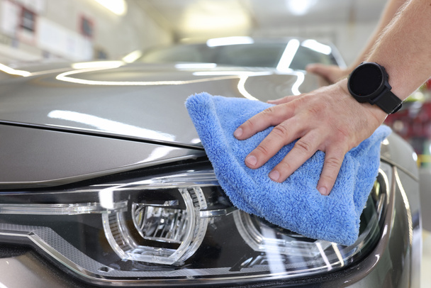 Man who decorates cars holds microfiber in hand and polishes car - Photo, Image
