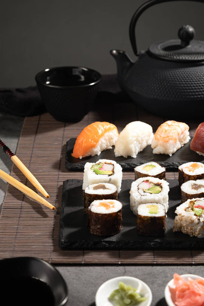 濃い色を背景に新鮮な寿司を閉じます。寿司セットと日本茶。縦型. - 写真・画像