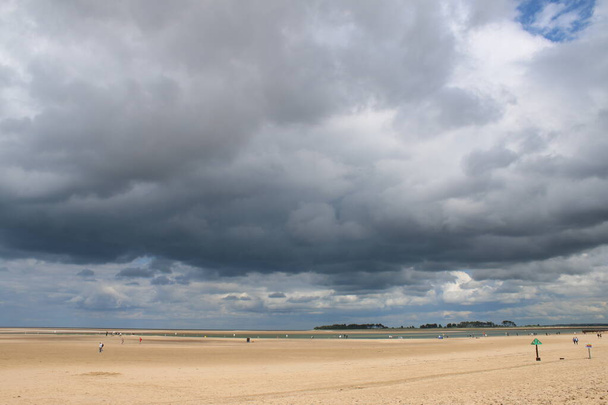 Superbe vue sur le vaste paysage de la vaste plage de sable fin à Wells Next the Sea in Norfolk East Anglia Angleterre Royaume-Uni par une journée d'été orageuse avec peu de gens marchant et marée à l'horizon - Photo, image