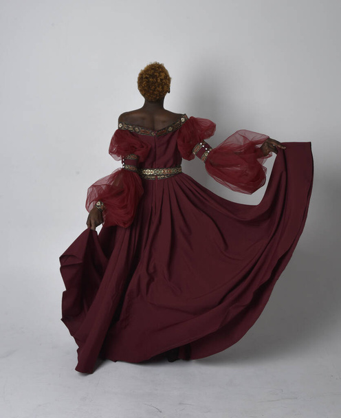Täyspitkä muotokuva kaunis Afrikkalainen nainen yllään pitkä punainen renessanssi keskiaikainen fantasia puku, seisoo poseeraa vaaleanharmaa studio tausta. - Valokuva, kuva