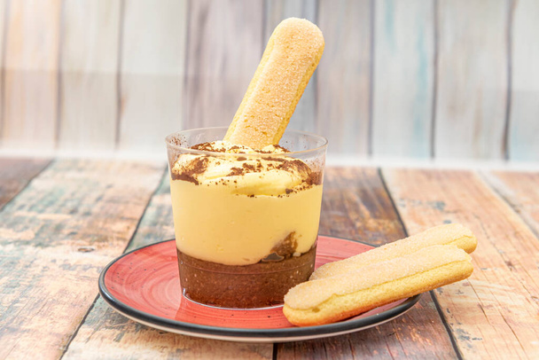 Tiramisu dessert en couches visibles à travers un verre, avec beaucoup de vanille et beaucoup de chocolat et de biscuits à tremper - Photo, image