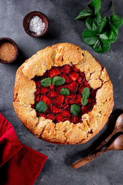 Homemade pie with strawberries on gray background top view, summer pastries with berries, vertical photo - Φωτογραφία, εικόνα