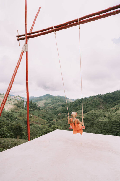 Woman is swinging on a big swing at tea plantation in mountain, Doi Mae Salong, Chiang Rai, Thailand - Photo, image