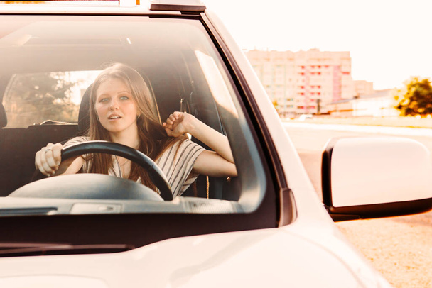 giovane bella donna che guida l'auto al tramonto. calda giornata di sole - Foto, immagini