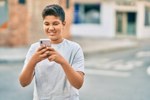 Adorable latin boy smiling happy using smartphone at the city. - Fotografie, Obrázek