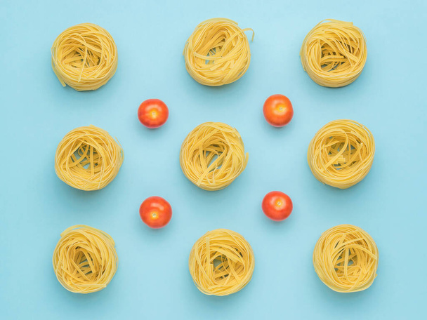 Background of pasta and fresh tomatoes on a blue background. Ingredients for making pasta. - Fotoğraf, Görsel