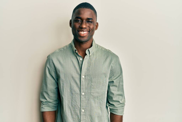 Νεαρός Αφροαμερικάνος που φοράει καθημερινά ρούχα με χαρούμενο και δροσερό χαμόγελο στο πρόσωπο. τυχερό άτομο.  - Φωτογραφία, εικόνα