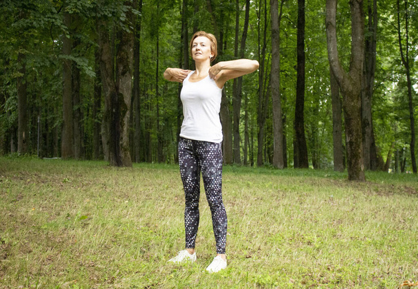 Krásná mladá žena chodí na sport do parku v přírodě. Žena se zabývá fitness ve sportovním oblečení. - Fotografie, Obrázek
