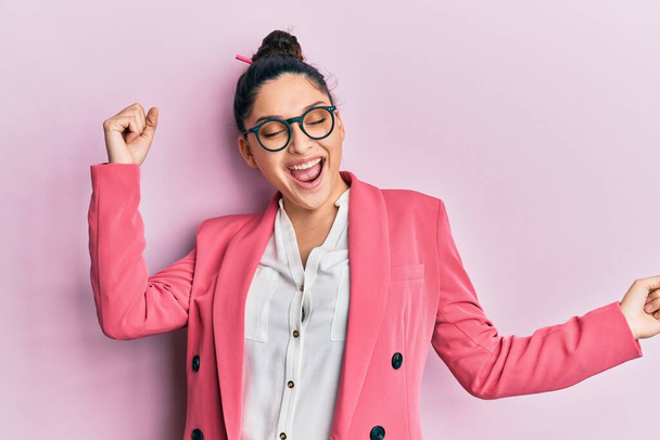 Beautiful middle eastern woman wearing business jacket and glasses dancing happy and cheerful, smiling moving casual and confident listening to music  - Photo, Image