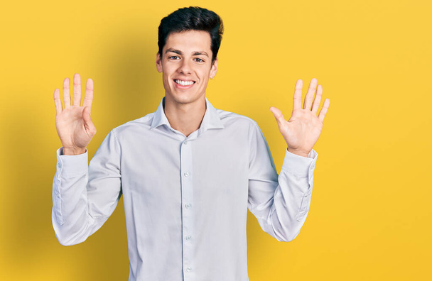 Jovem homem de negócios hispânico vestindo roupas de negócios mostrando e apontando para cima com os dedos número dez enquanto sorri confiante e feliz.  - Foto, Imagem