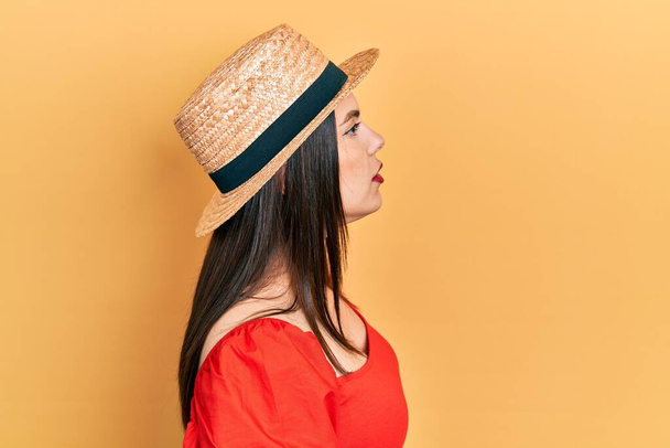 jonge Spaanse vrouw dragen zomer hoed op zoek naar kant, ontspannen profiel poseren met natuurlijke gezicht met zelfverzekerde glimlach.  - Foto, afbeelding