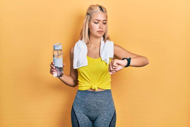 Beautiful blonde sports woman using smart watch relaxed with serious expression on face. simple and natural looking at the camera.  - Foto, Imagen