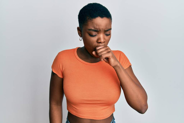 A fiatal afro-amerikai nő alkalmi narancssárga pólót visel rossz közérzet és köhögés tüneteként hideg vagy hörghurut. az egészségügyi ellátás fogalma.  - Fotó, kép