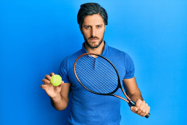 Young hispanic man playing tennis holding racket and ball skeptic and nervous, frowning upset because of problem. negative person.  - Φωτογραφία, εικόνα