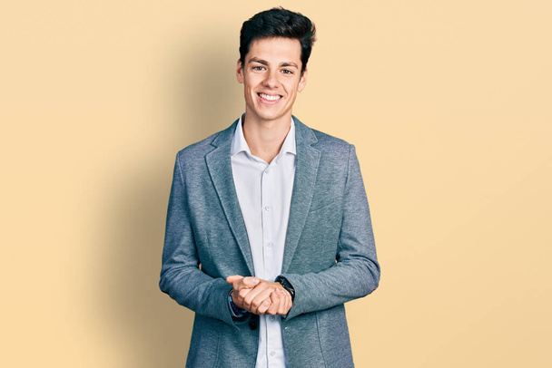 Молодий іспаномовний чоловік одягнений в діловий одяг руками і схрещеними пальцями посміхається розслабленим і веселим. успіх і оптимізм
  - Фото, зображення