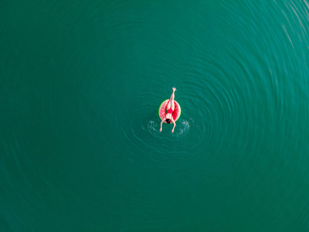 молодая счастливая женщина плавает в голубой лазурной воде на надувном кольце круга летних каникул - Фото, изображение