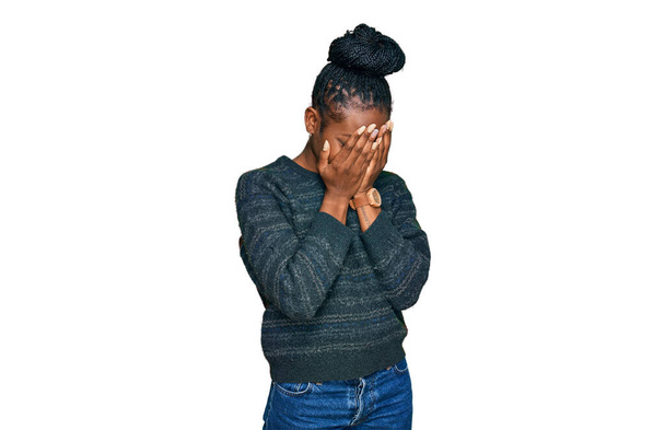 Junge afrikanisch-amerikanische Frau in lässiger Kleidung mit traurigem Gesichtsausdruck, der das Gesicht mit Händen bedeckt, während sie weint. Depressionskonzept.  - Foto, Bild
