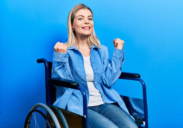 Piękna biała kobieta siedząca na wózku inwalidzkim podekscytowana sukcesem z podniesionymi ramionami i zamkniętymi oczami świętującymi zwycięstwo uśmiechnięta. koncepcja zwycięzcy.  - Zdjęcie, obraz