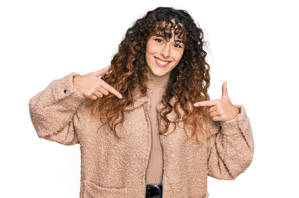Young hispanic girl wearing winter clothes looking confident with smile on face, pointing oneself with fingers proud and happy.  - Foto, afbeelding