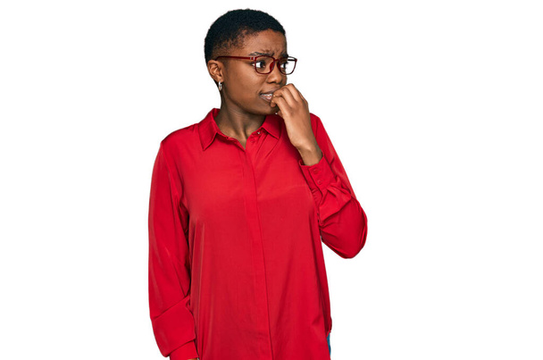 Fiatal afro-amerikai nő alkalmi ruhát és szemüveget visel, stresszesnek és idegesnek tűnik, miközben a kezei körmöket harapdálnak. szorongás.  - Fotó, kép