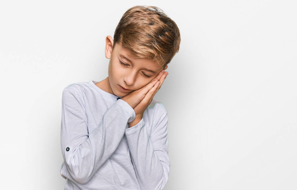 Little caucasian boy kid wearing casual clothes sleeping tired dreaming and posing with hands together while smiling with closed eyes.  - Photo, Image
