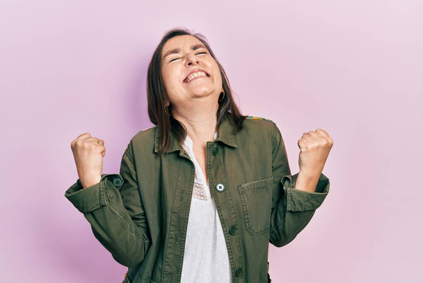 Middle age hispanic woman wearing casual clothes very happy and excited doing winner gesture with arms raised, smiling and screaming for success. celebration concept.  - Фото, зображення