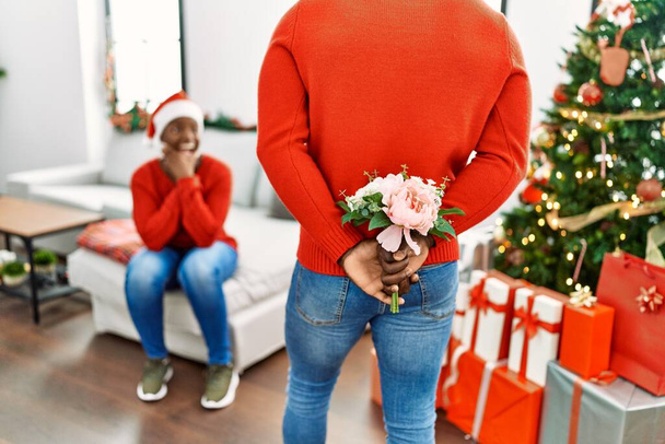 Africano americano homem surpreendente sua namorada com buquê de flores em casa. - Foto, Imagem