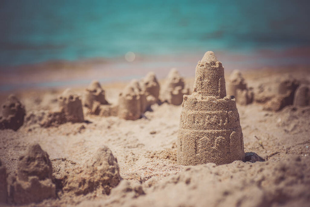 Château de sable debout sur la plage. Concept de vacances de voyage. - Photo, image